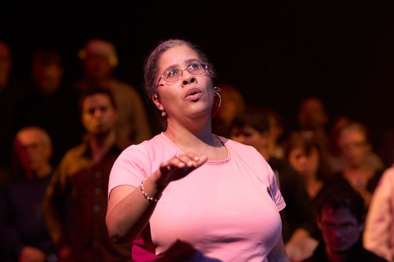 Sarah standing in front of seated choir members